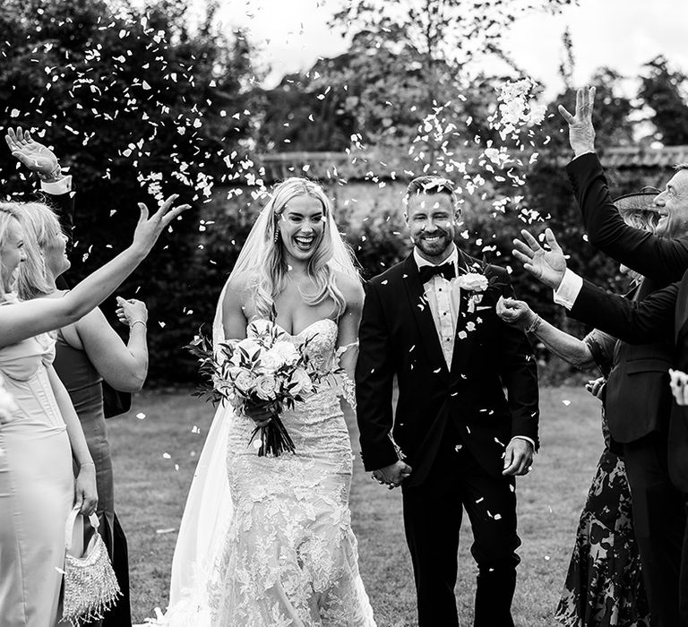 groom-in-black-tuxedo-and-bride-at-outdoor-wedding-confetti-moment