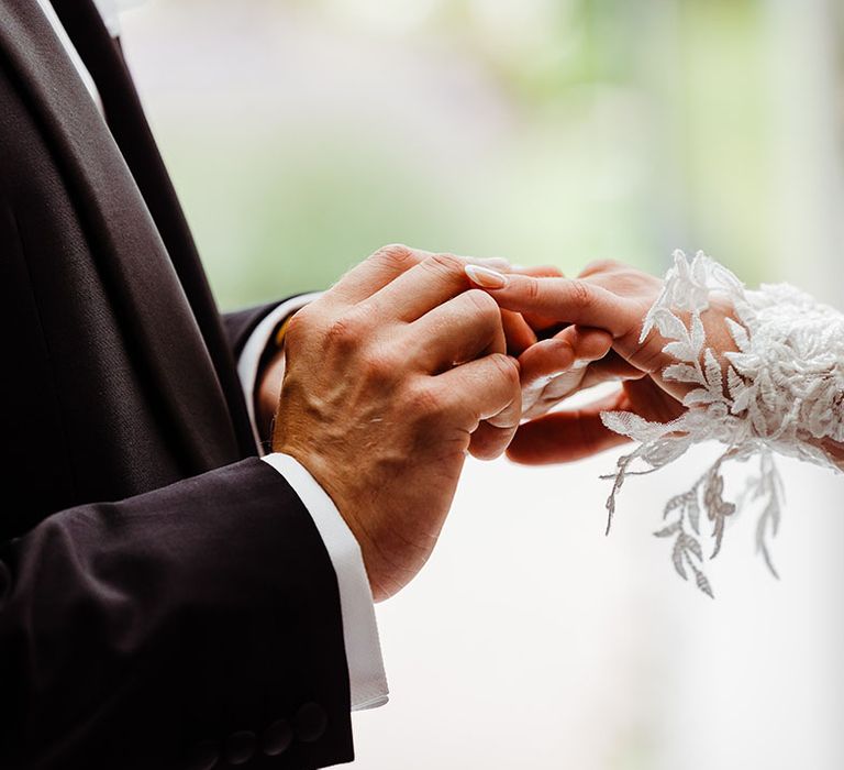 groom-puts-ring-on-brides-finger-during-ring-exchange