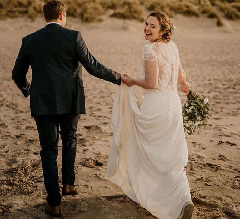 bride and groom holding hands on the beach for Irish coastal wedding venue