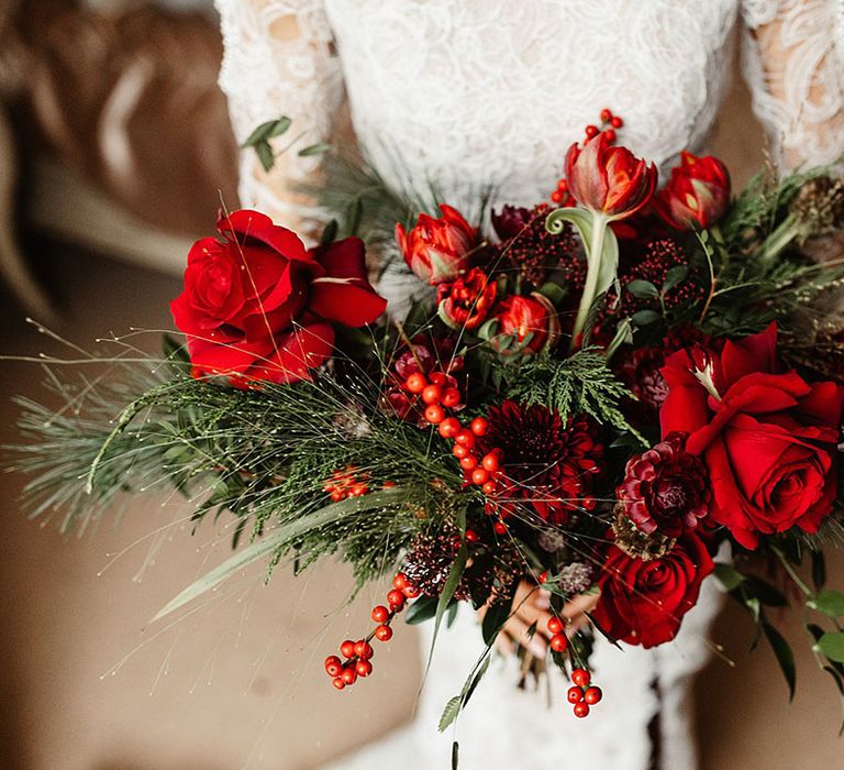 bride-holding-red-rose-wedding-bouquet-with-foliage