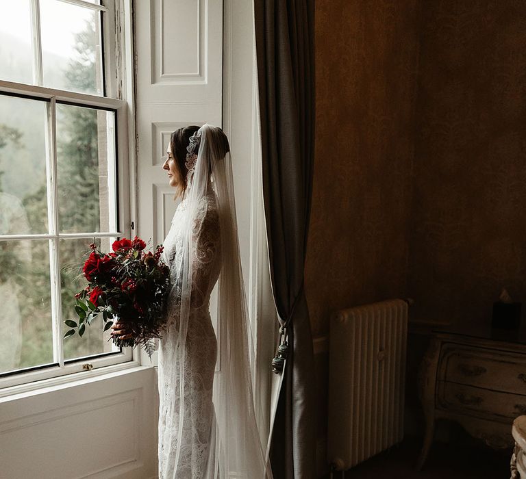 bride-wearing-long-sleeve-lace-wedding-dress-with-veil-and-rose-bouquet