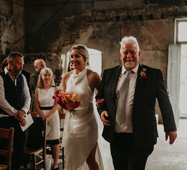 father-of-the-bride-walks-bride-in-satin-wedding-dress-down-the-aisle