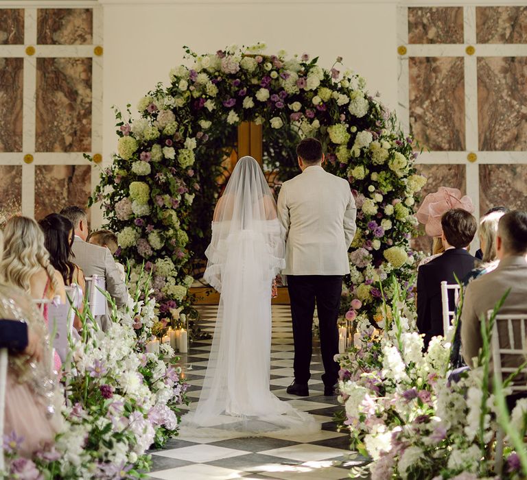 bride-and-groom-at-wedding-ceremony-with-flower-arch-altar-decorations