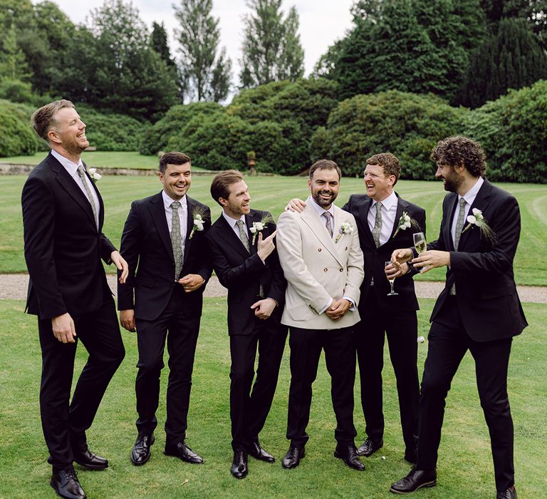 groomsmen-wearing-black-suits-with-the-groom-wearing-a-cream-suit-jacket