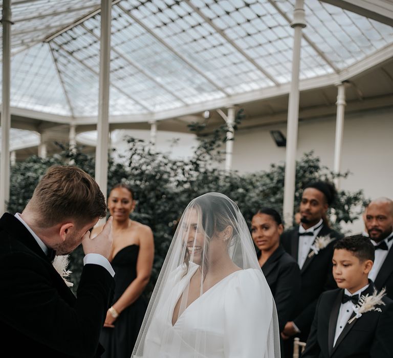 bride-wearing-ruffle-veil-facing-groom-at-the-end-of-the-aisle