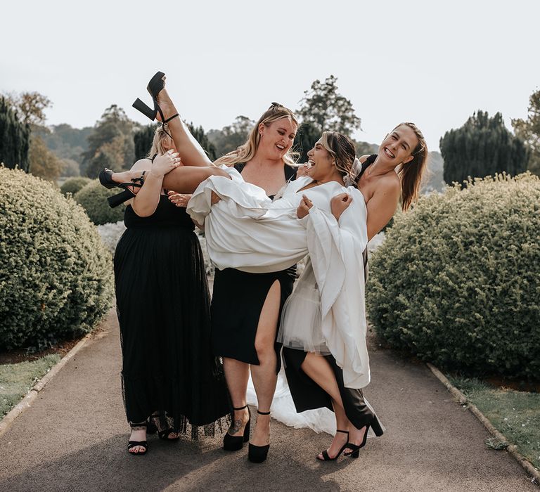 bridesmaids-in-black-bridesmaid-dresses-lift-bride-in-funny-photo