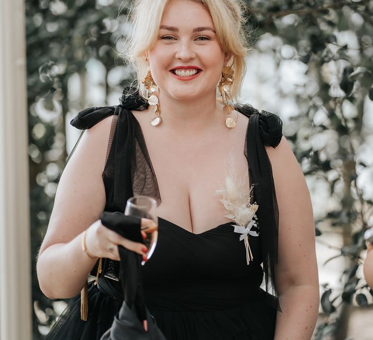 wedding-guest-wearing-bow-sleeve-black-dress-with-gold-earrings