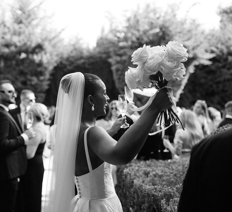 bride-holds-white-rose-bouquet-in-the-air