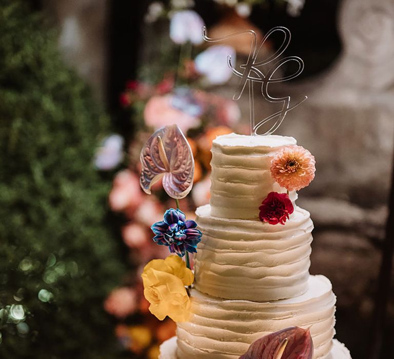 Five tier white frosted wedding cake with personalised cake topper and colourful flowers