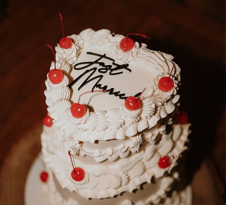 iced heart shaped wedding cake decorated with maraschino cherries with 'Just Married' black icing