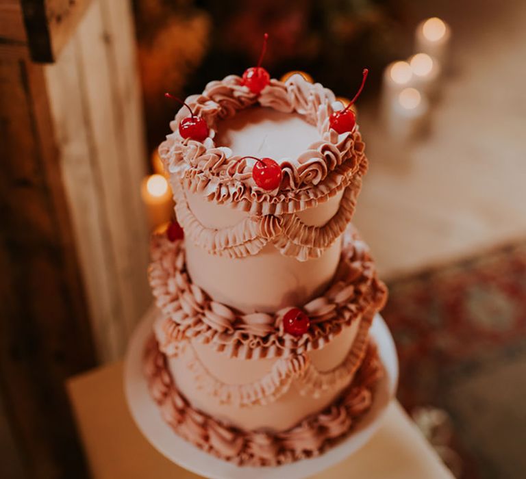 Light pink two tier retro wedding cake decorated with maraschino cherries