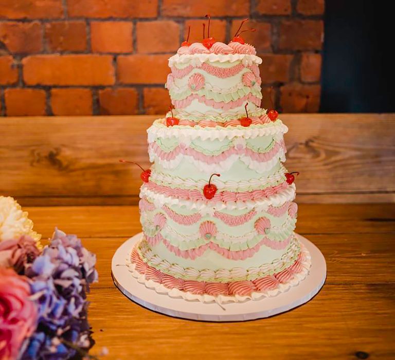 three tier pastel wedding cake decorated with cherries