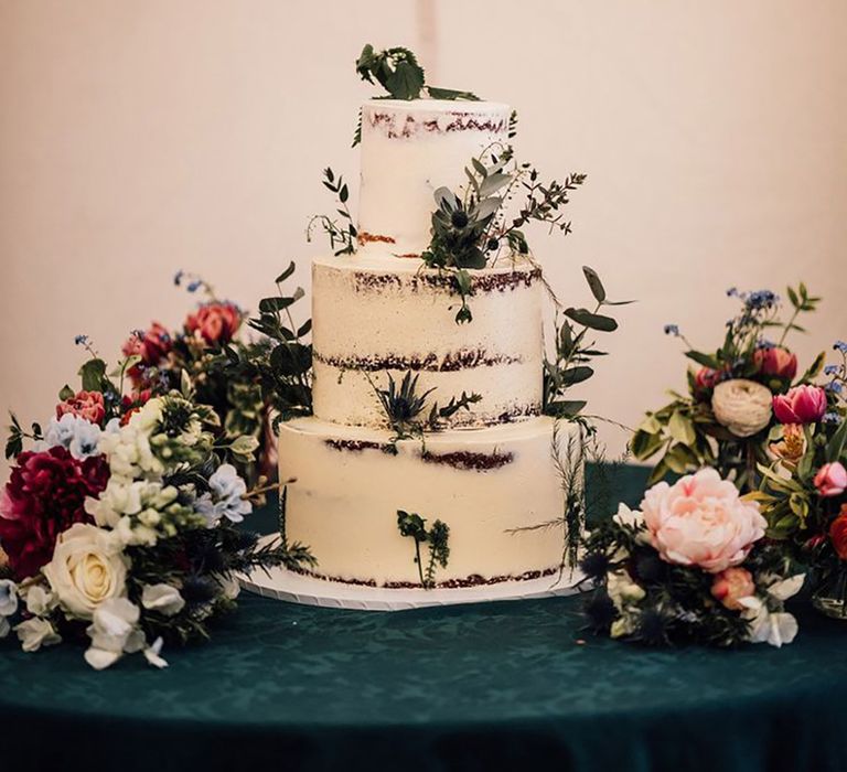 Three tier semi-naked rustic wedding cake decorated with white frosting