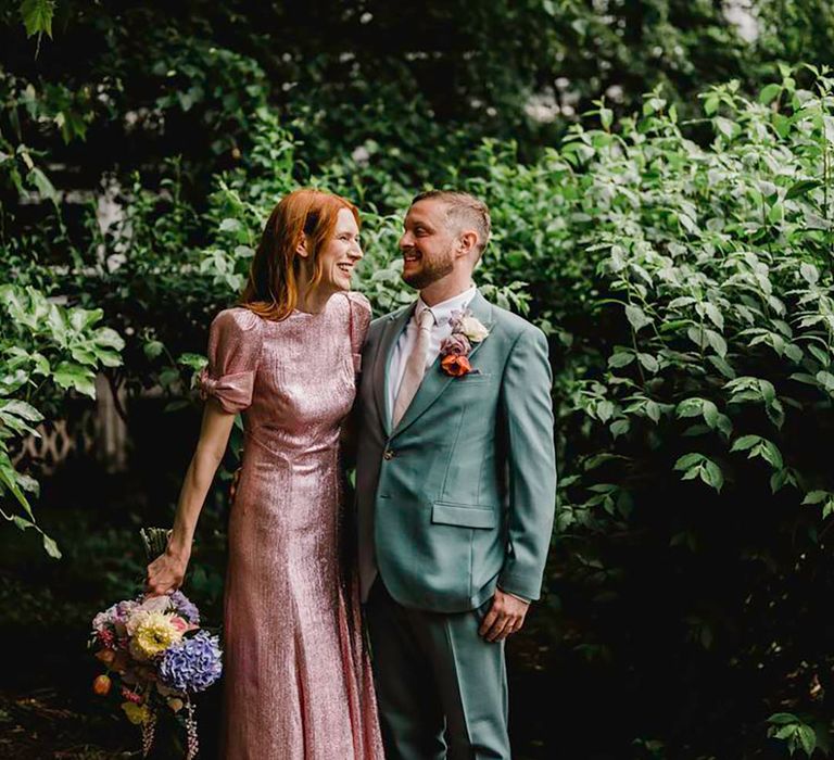 groom wearing a mint teal wedding suit with colourful buttonhole and light pink tie