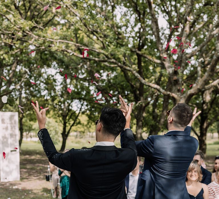 flower-men-walking-down-the-aisle-together-at-outdoor-wedding-throwing-confetti