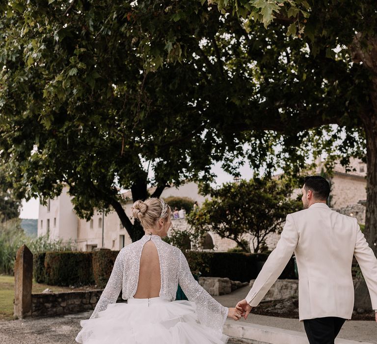 groom-in-white-tuxedo-walking-with-bride-in-tulle-layered-skirt