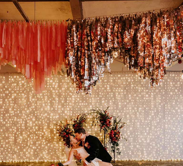 groom-kisses-bride-decorated-with-streamers-and-fairy-lights