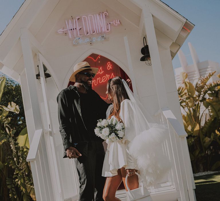 bride-in-short-wedding-dress-with-white-bag-and-shoes-with-groom