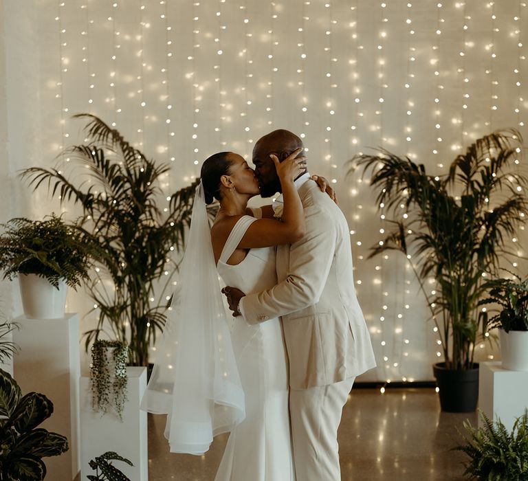 bride-and-groom-share-first-kiss-as-married-couple-at-industrial-wedding-with-fairy-lights