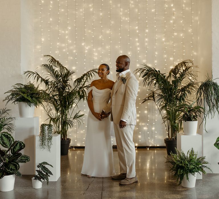 bride-and-groom-standing-at-altar-decorated-with-greenery