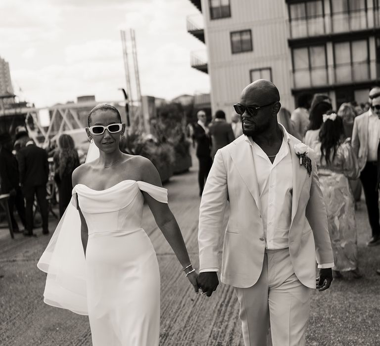 bride-in-off-the-shoulder-martina-liana-wedding-dress-and-sunglasses-with-groom-in-cream-and-white-suit