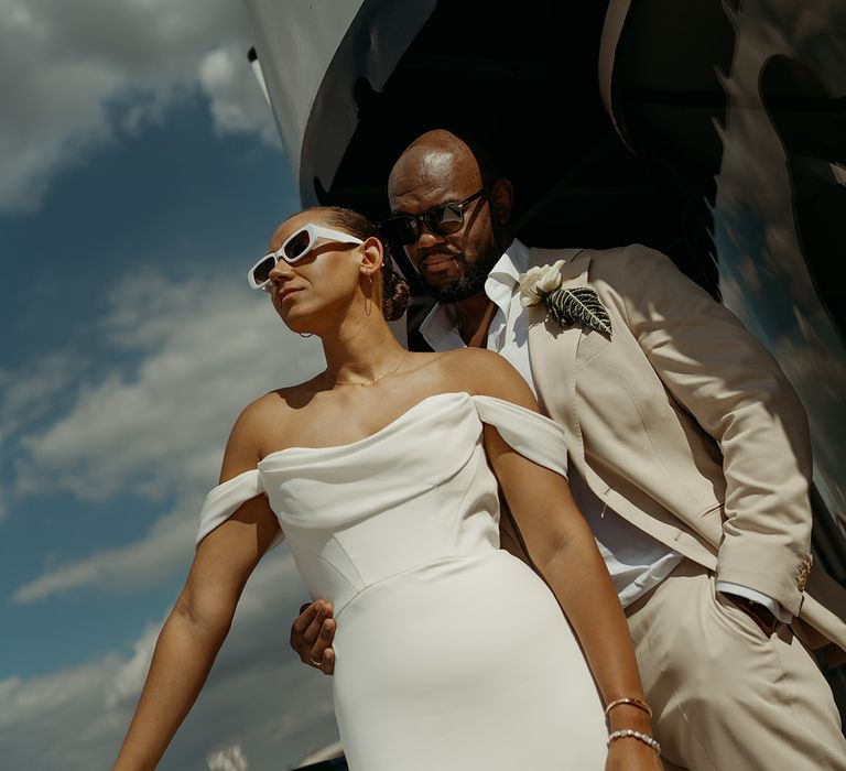 groom-in-cream-suit-embracing-bride-in-martina-liana-wedding-dress-with-sunglasses