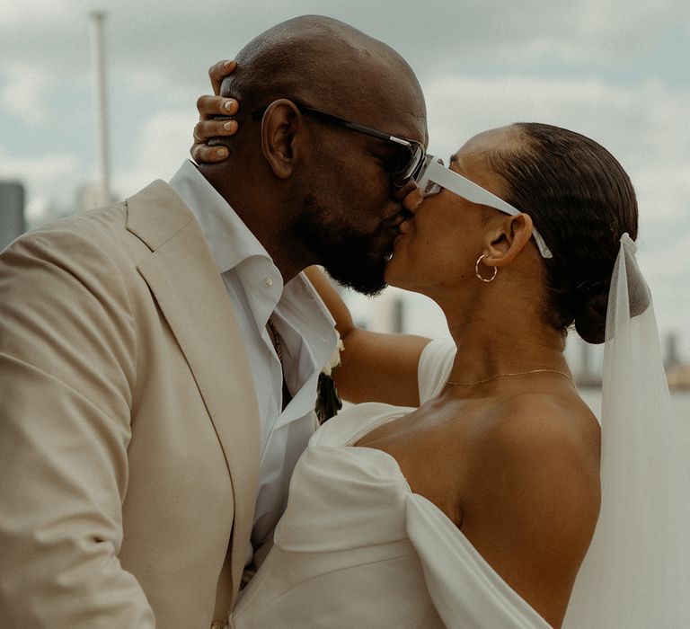 groom-in-cream-suit-kissing-bride-in-off-the-shoulder-wedding-dress