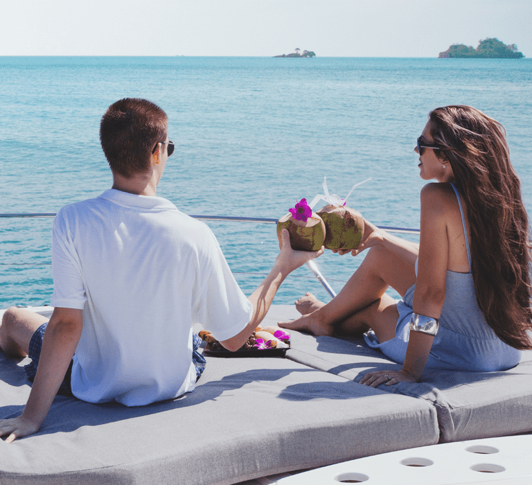 Couple enjoying coconut drinks together on a boat trip during their honeymoon.