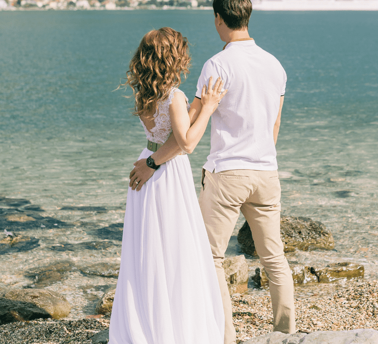 Couple embracing each other while gazing at a mountain and sea view during their honeymoon.