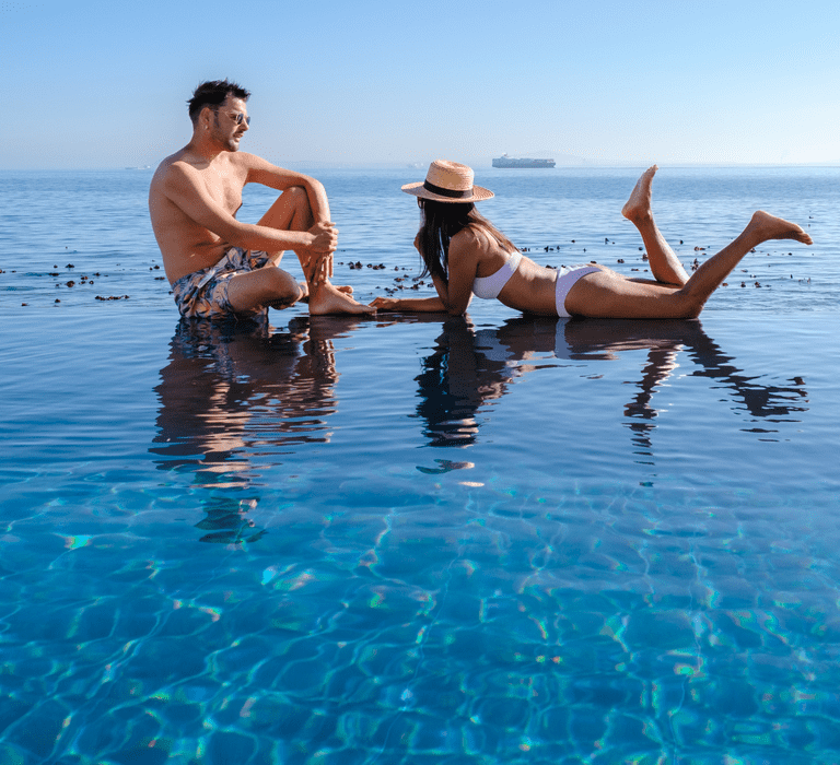 Couple relaxing in the sea during their honeymoon, with the woman lying on her front and the man sitting beside her.