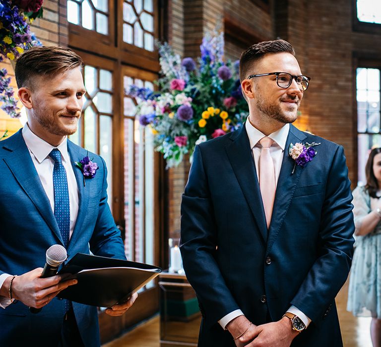 groom-in-navy-wedding-suit-seeing-groom-walking-down-the-aisle