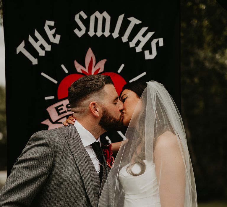 bride-and-groom-kiss-in-front-of-banner-sign