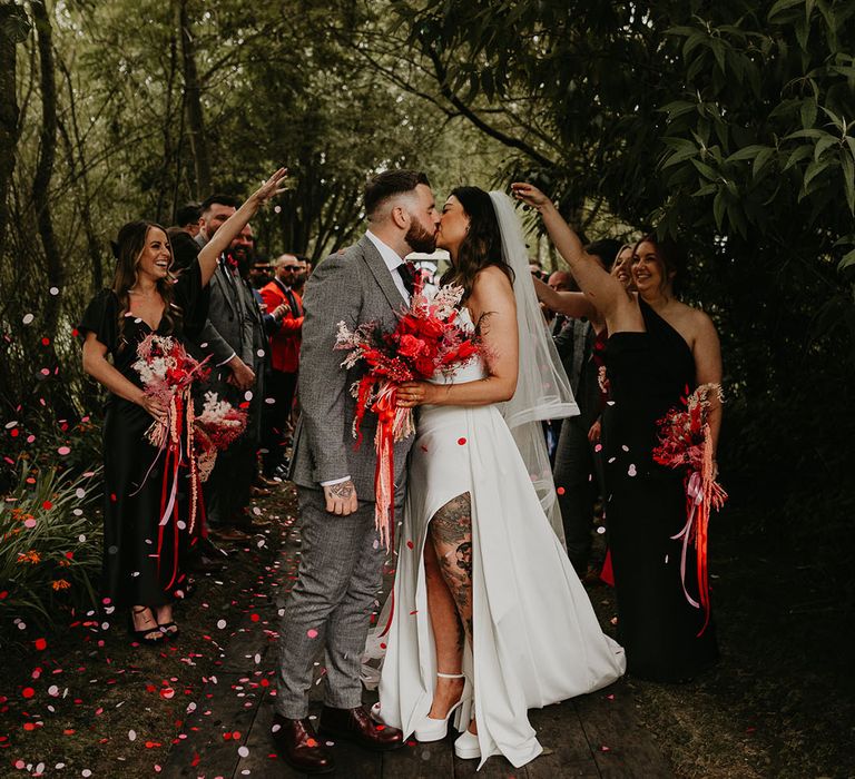 bride-in-front-slit-dress-with-tattoos-kisses-groom