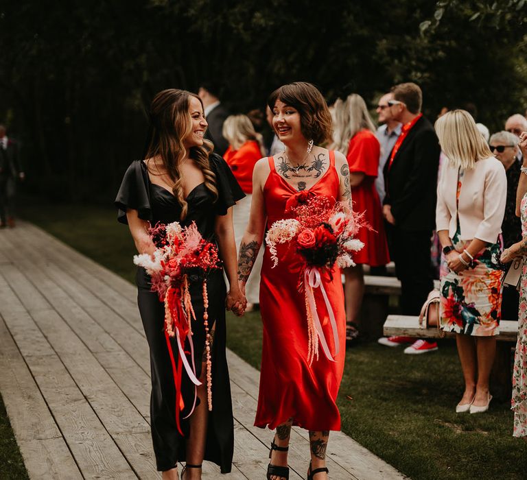 bridesmaids-in-red-and-black-satin-dresses-walk-down-the-aisle