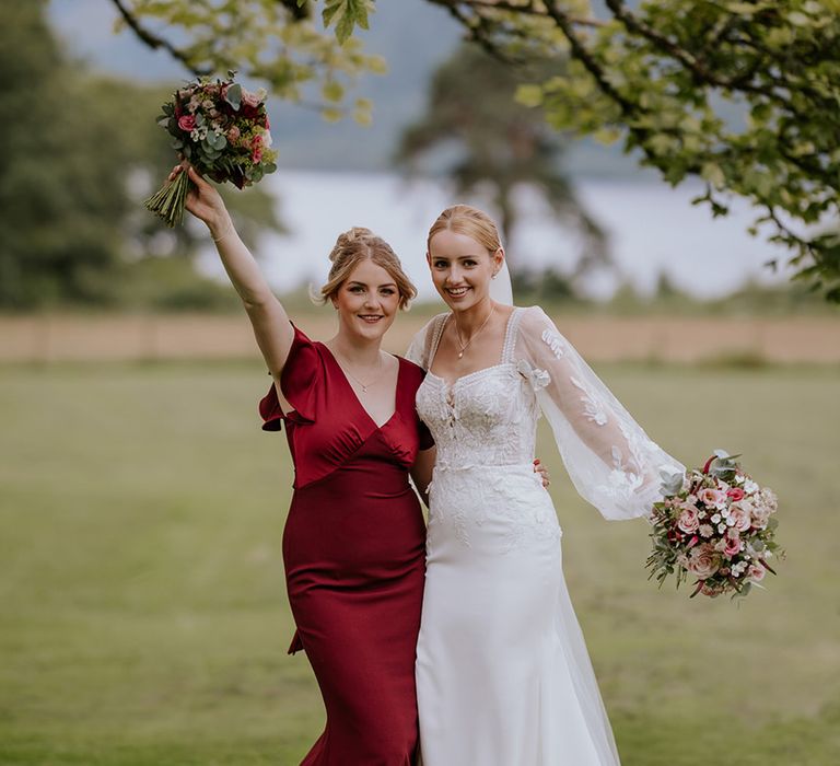 bridesmaid-in-satin-burgundy-dress-with-bride-in-sheer-sleeve-wedding-dress