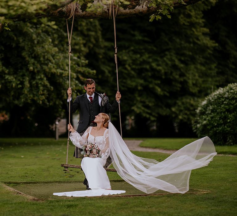 groom-pushes-bride-on-wooden-swing