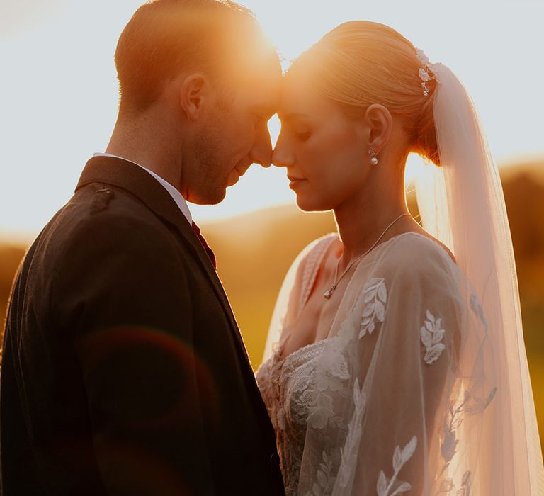 sunset-wedding-photo-with-bride-and-groom-resting-their-foreheads-together