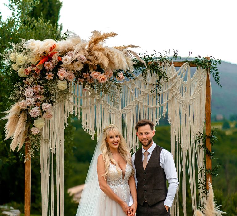 bride-and-groom-with-macrame-wedding-altar-decor-and-dried-pampas-grass