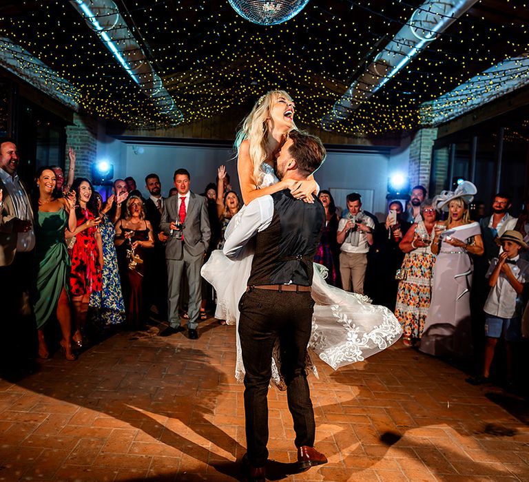 groom-lifts-bride-for-first-dance-under-disco-ball