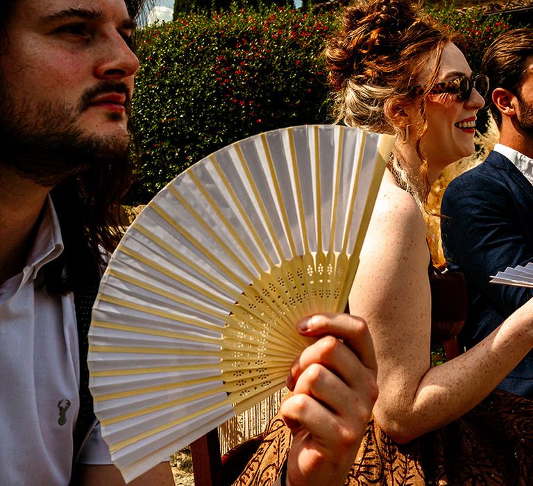 wedding-guests-waving-fans-at-wedding