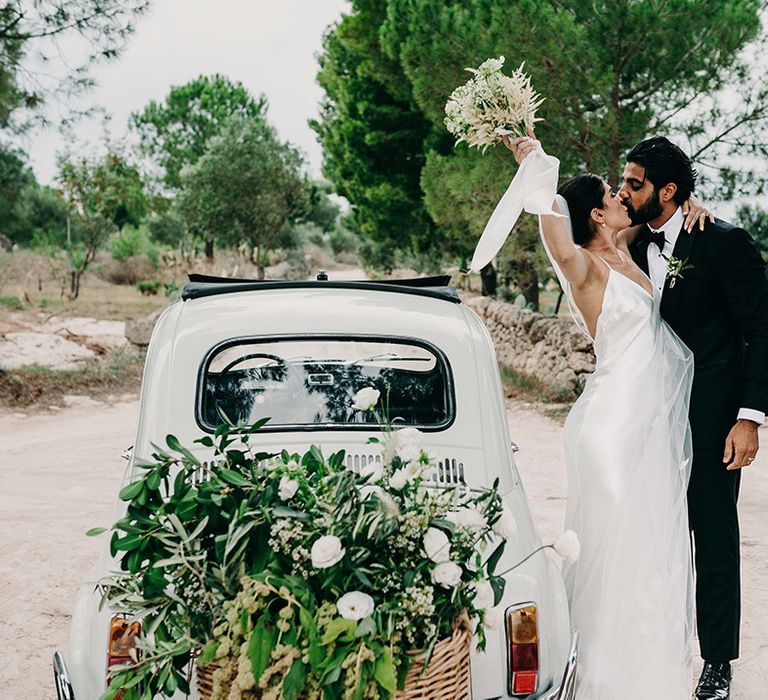 vintage-small-wedding-car-with-bride-and-groom-sharing-a-kiss