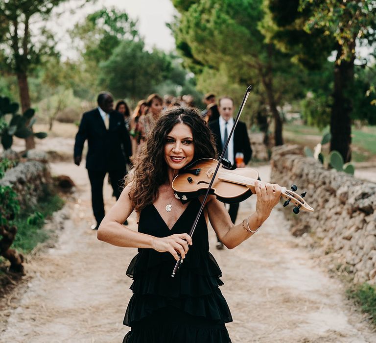 violinist-plays-music-as-guests-walk-to-wedding-venue