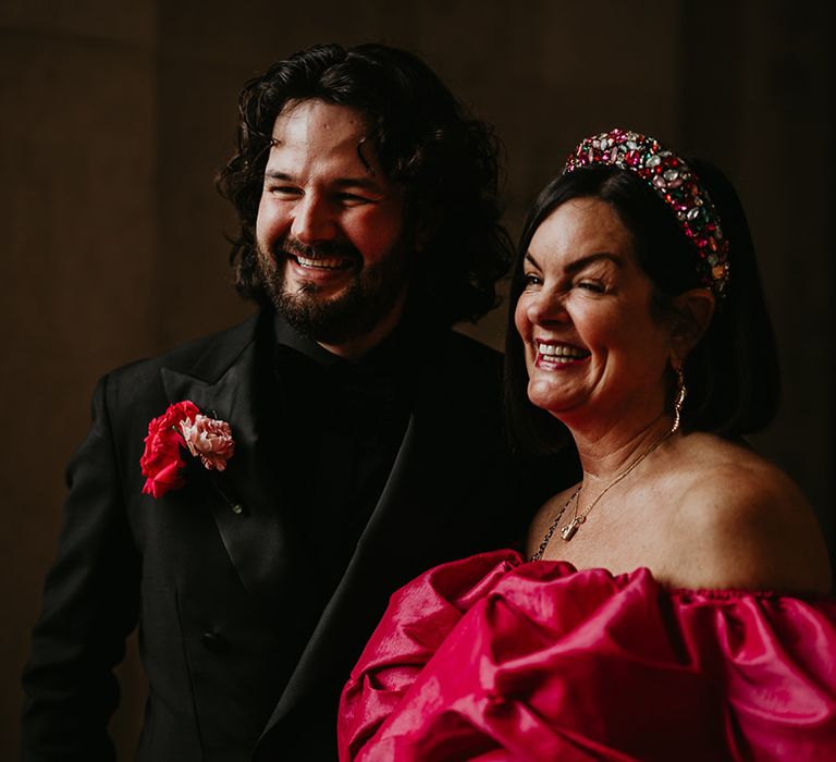 groom-smiling-with-wedding-guest-in-pink-dress-and-crown