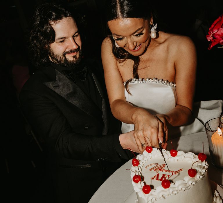 heart-shaped-wedding-cake-with-cherries-cut-by-bride-and-groom
