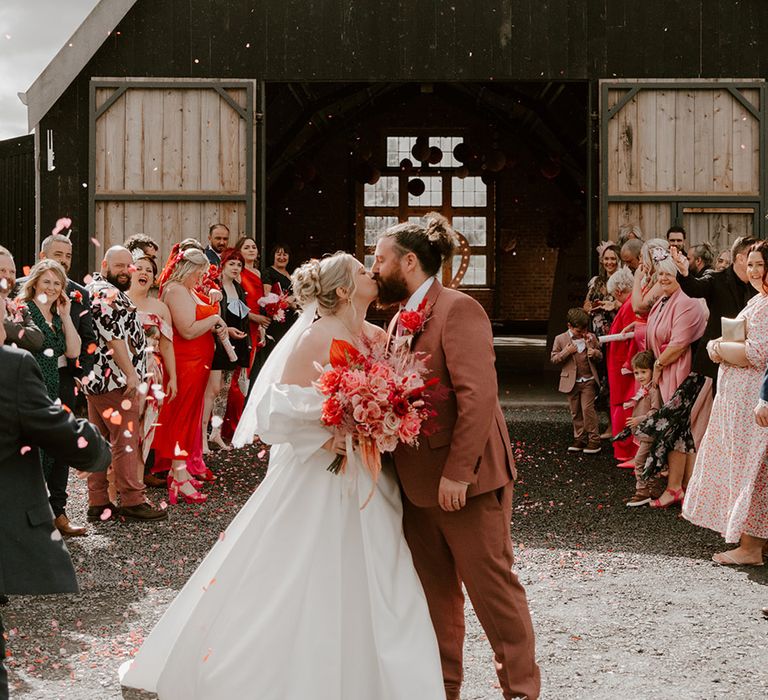 bride-in-puff-sleeve-dress-and-groom-in-pink-suit-kiss