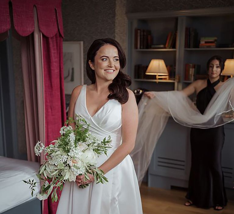 bride wearing classic traditional wedding dress with front slit, while holding bouquet