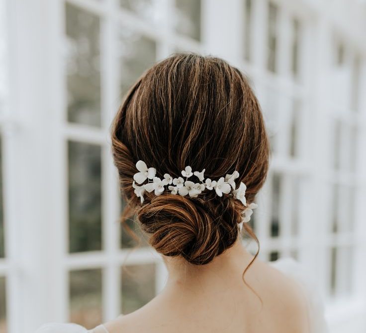 Bride with Elegant Bun Hairstyle with Enamel White Flower Hair Accessory