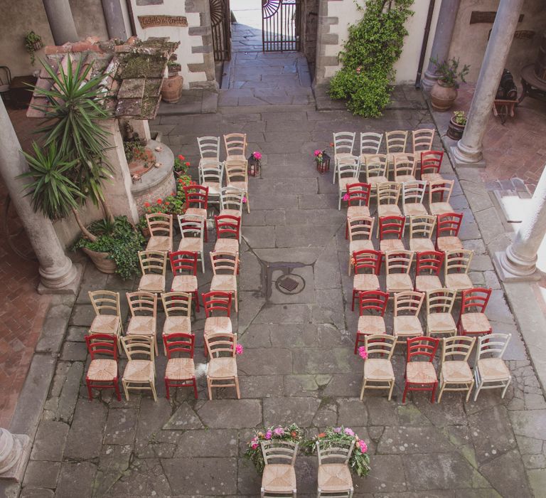 Outdoor Wedding Ceremony in Tuscany With Bright Florals And Rustic Wooden Seating