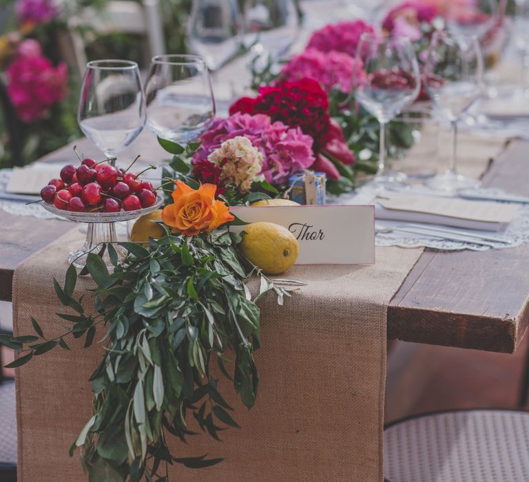 Outdoor Wedding Ceremony in Tuscany With Bright Florals And Rustic Wooden Seating