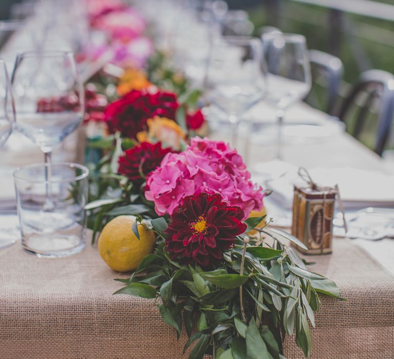 Outdoor Wedding Ceremony in Tuscany With Bright Florals And Rustic Wooden Seating